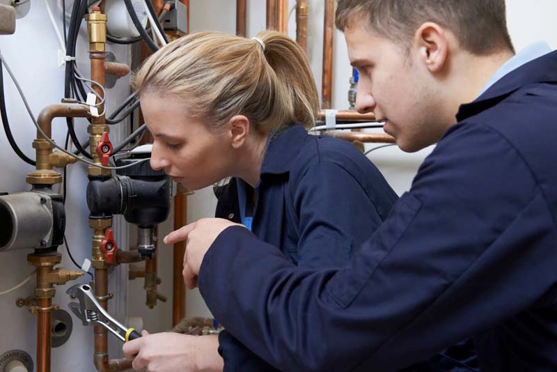 Women and man fixing water pump